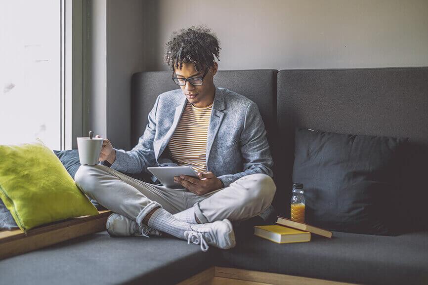 Student reading tablet with cup of coffee