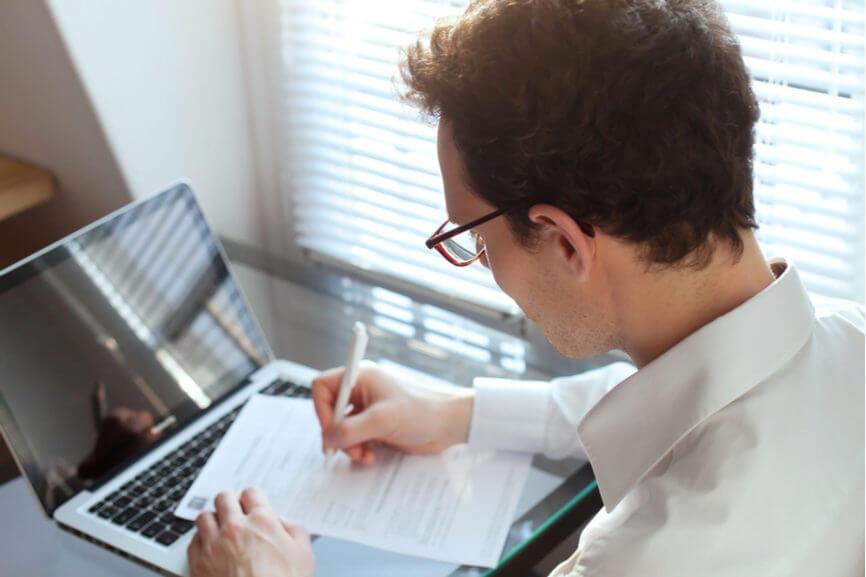 man edits his resume in front of his computer