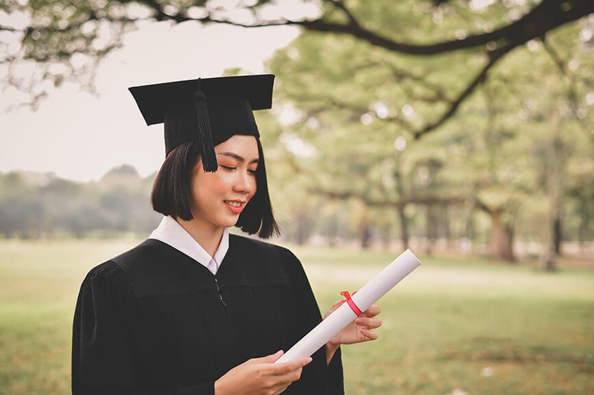 Recent graduate looking at diploma outside