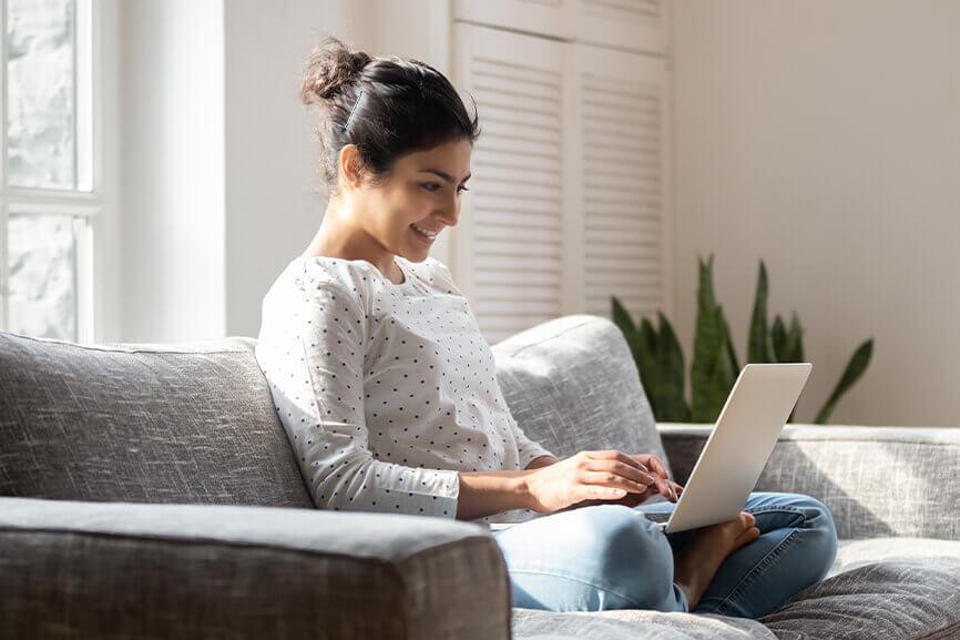 Young woman typing on laptop on sofa