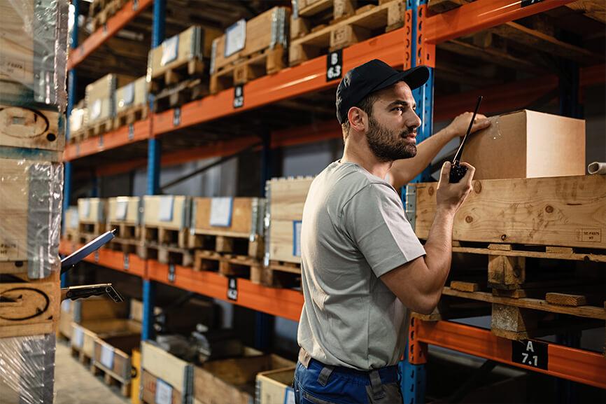 Warehouse worker talking on walkie talkie in the warehouse