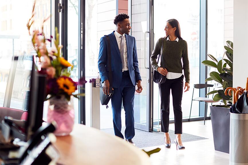 Male and female coworkers walking into the office together