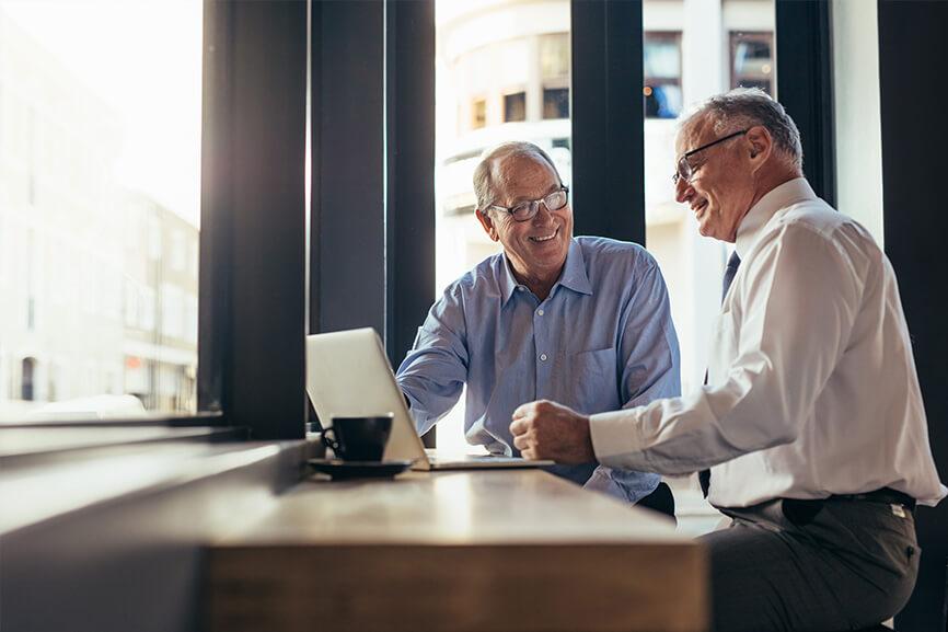 Two older professionals talking to each at a coffee shop