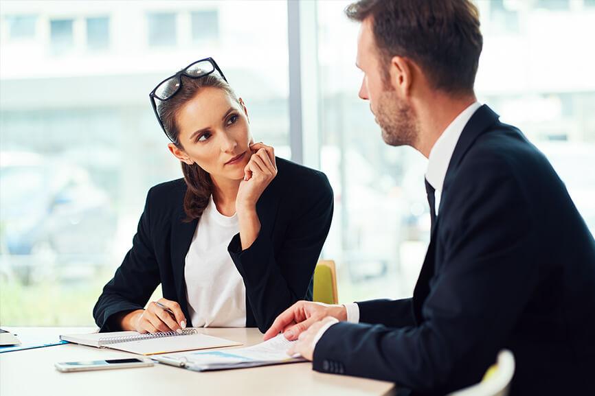 Male and female professionals talking with documents laid out on desk