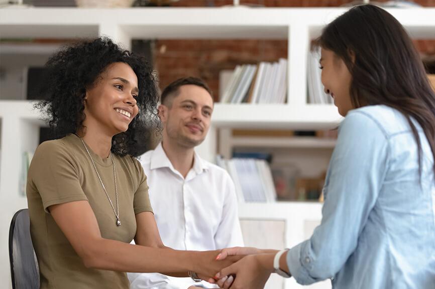 Two people greeting young woman to an interview