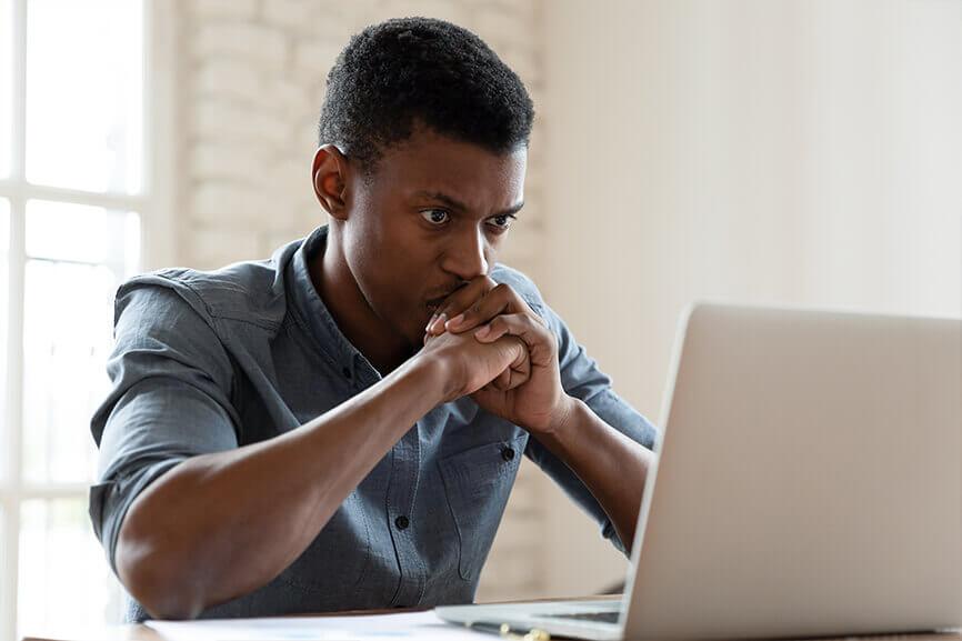 Young male deep in thought while in front of laptop