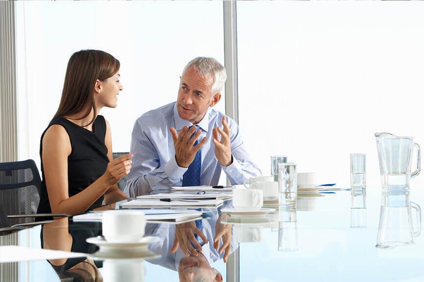 Older man talking to woman at a meeting table