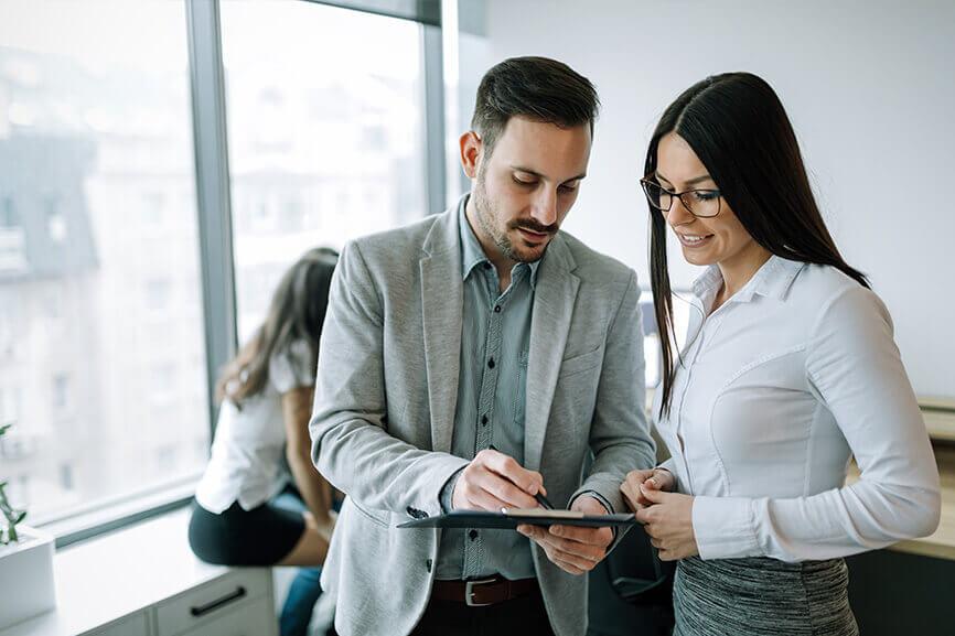 Male coworker showing another coworker something on the tablet at work