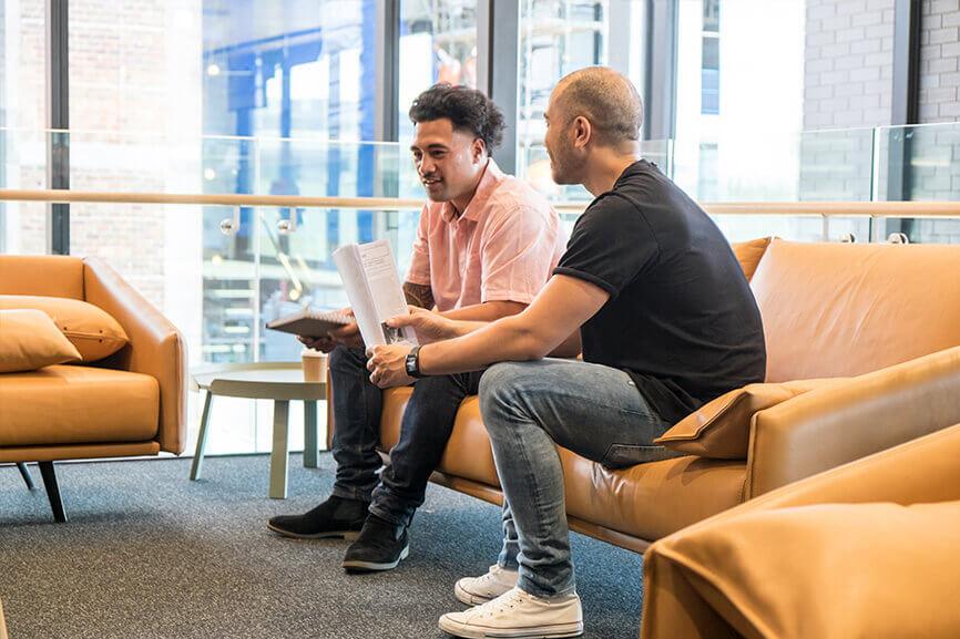 Two men talking to each other casually on office couch