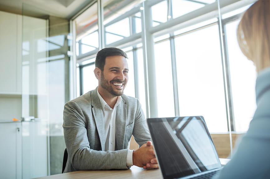 Woman in front of laptop talking to a happy looking man